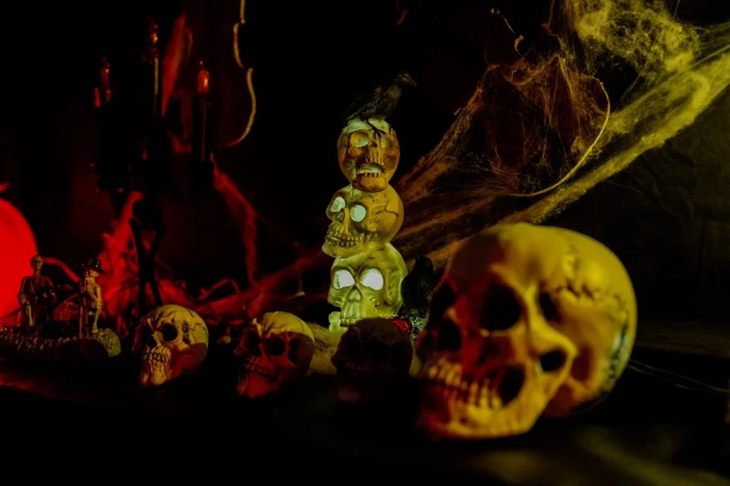 Griezelig Halloween-decor met opgestapelde oplichtende schedels, spinnenwebben en een raaf β Haunted House Heeswijk-Dinther en Loosbroek